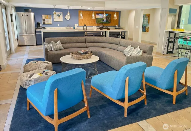 a living room with stainless steel appliances furniture a rug and a kitchen view