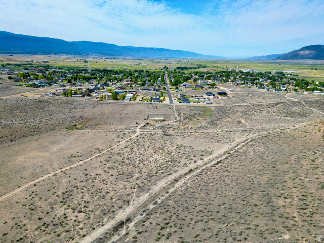 600 East E Street Moroni, UT 84646 - Photo 23 of 38 Expansive undeveloped land featuring natural desert vegetation, a long unpaved road, and distant mountain ranges