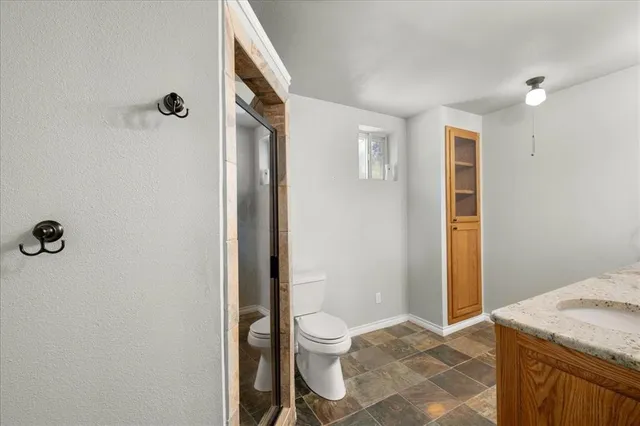 a bathroom with a granite countertop sink a toilet and shower