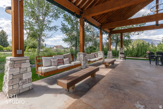 1188 South Old Trappers Loop Road Huntsville, UT 84317 - Photo 7 of 92 Expansive outdoor covered patio featuring exposed timber beams, stone-clad pillars, and a concrete floor
