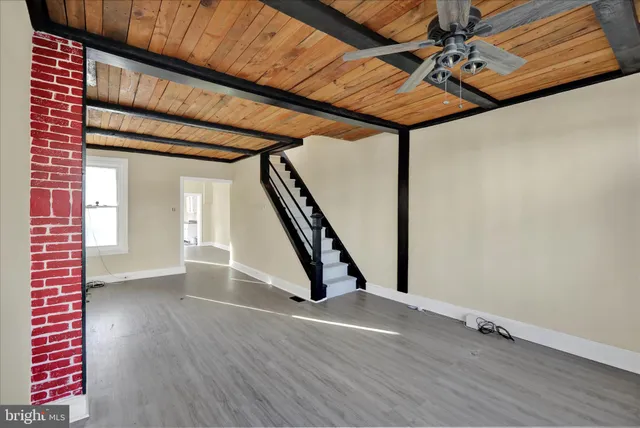 a view of an empty room with wooden floor and stairs