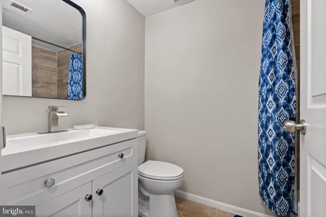 a bathroom with a granite countertop sink toilet and a mirror