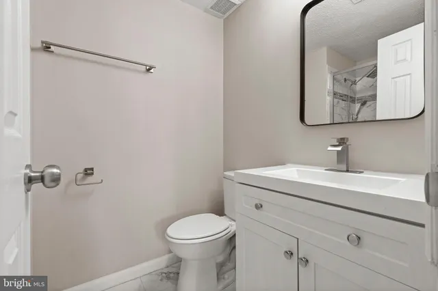 a bathroom with a toilet sink vanity and mirror