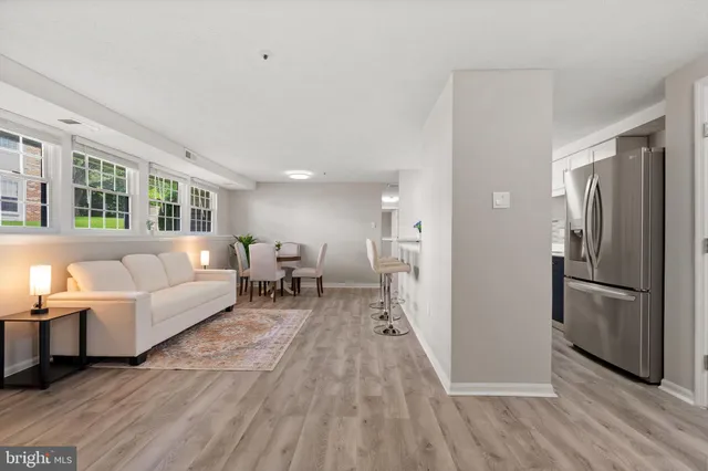 a living room with furniture and a refrigerator