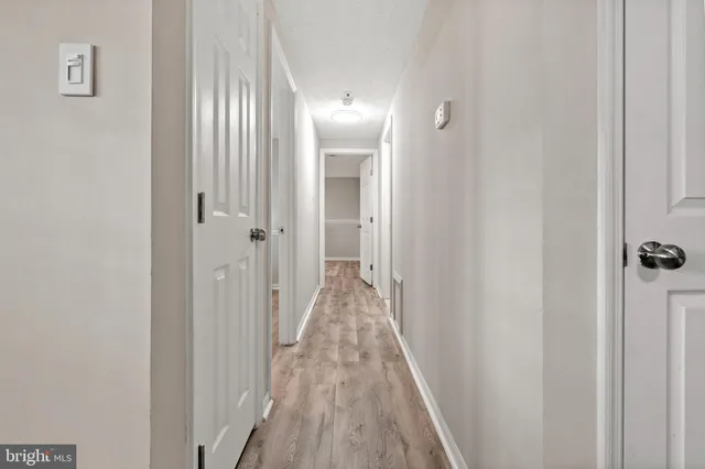 a view of a hallway with wooden floor and a bathroom