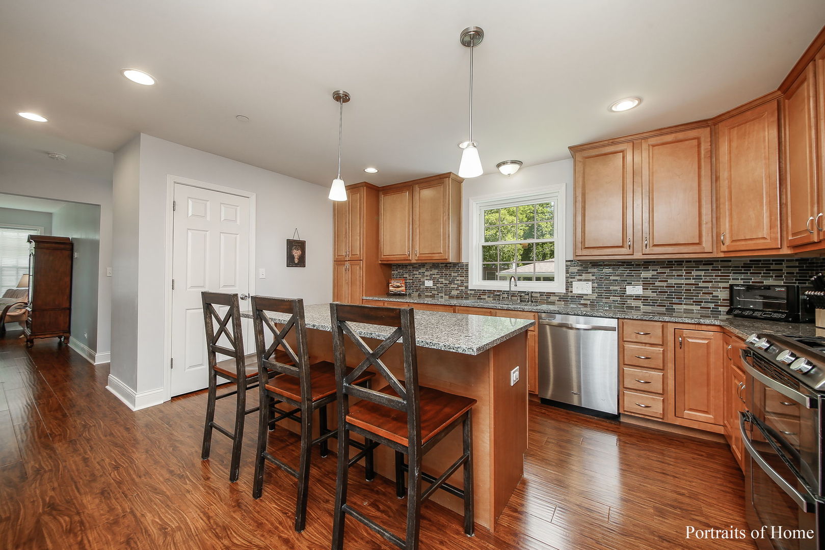 231 Highland Road Willowbrook, IL 60527 - Photo 6 of 38 a kitchen with stainless steel appliances granite countertop wooden floors stove and white cabinets