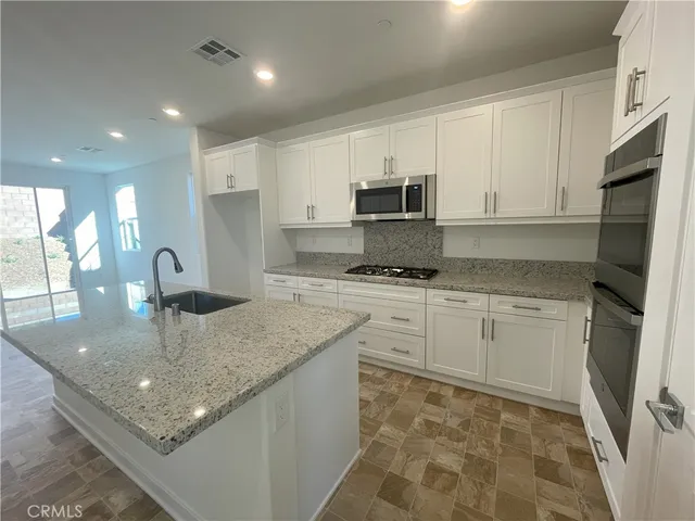 a kitchen with kitchen island granite countertop a sink appliances cabinets and a counter top space
