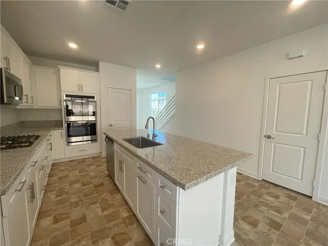 a kitchen with stainless steel appliances granite countertop a stove top oven a sink and dishwasher