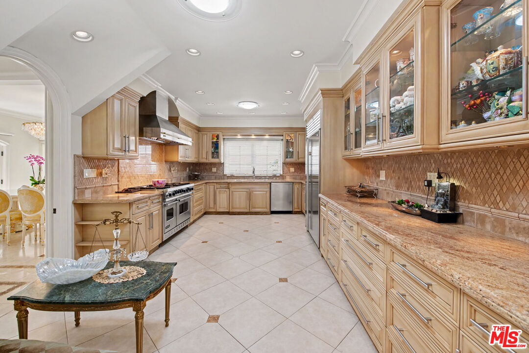 204 Foothill Road Beverly Hills, CA 90210 - Photo 11 of 38 a kitchen with stainless steel appliances kitchen island granite countertop a stove and a sink