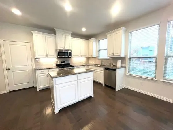 a kitchen with granite countertop white cabinets and white appliances