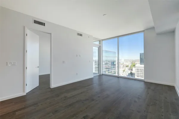 a view of an empty room with wooden floor and a window