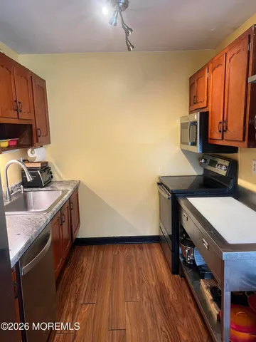 a kitchen with a sink a stove a microwave and wooden floor