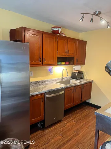 a kitchen with kitchen island granite countertop a sink a stove and wooden cabinets