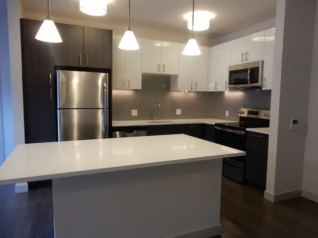 a kitchen with kitchen island a sink dishwasher a refrigerator with wooden floor