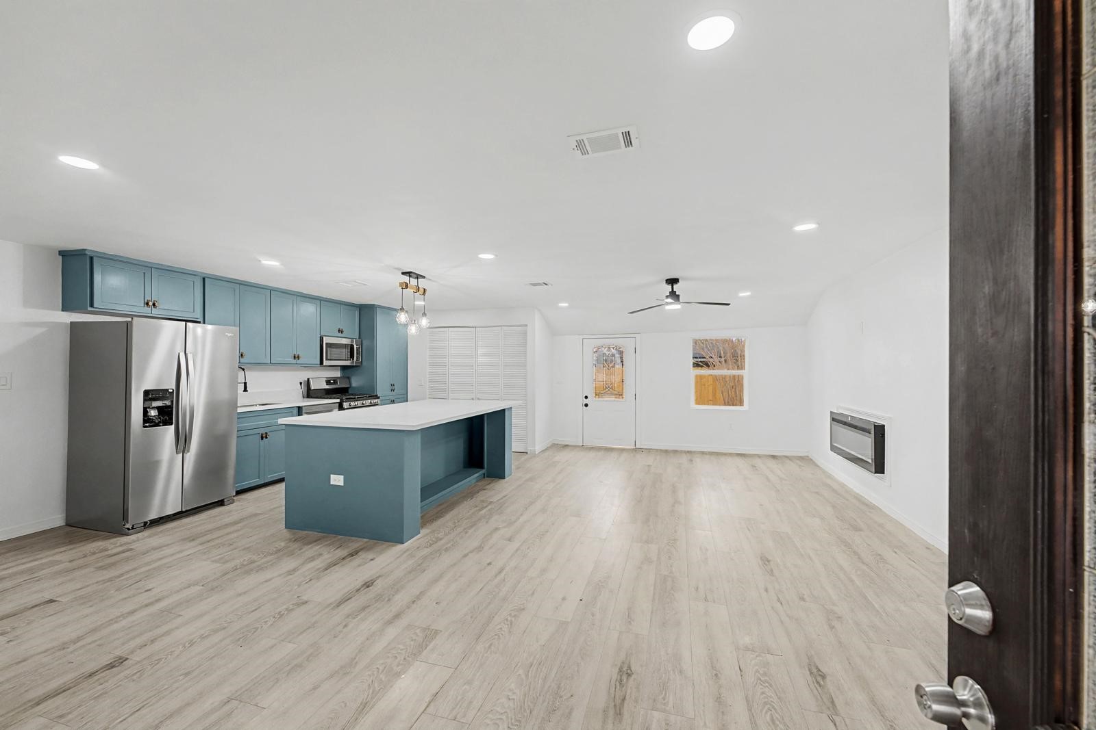 5719 Southwind Street Houston, TX 77033 - Photo 4 of 15 a large kitchen with stainless steel appliances kitchen island a sink dishwasher a refrigerator and a oven with wooden floor