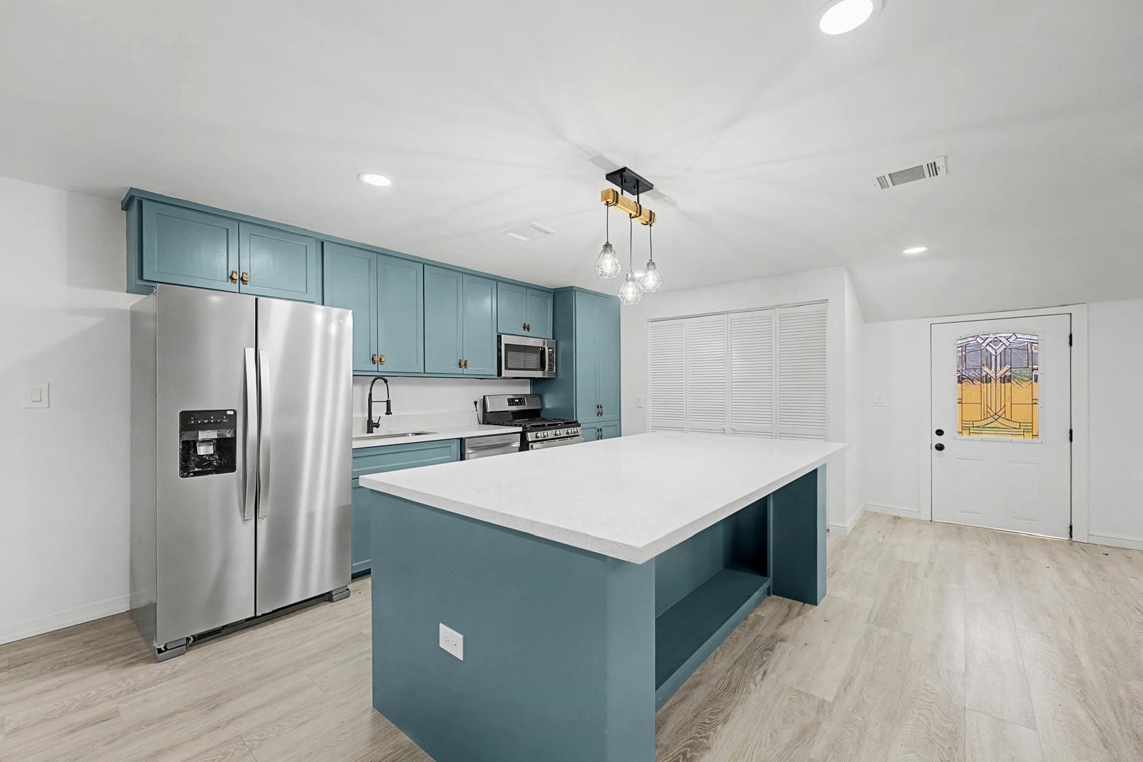 5719 Southwind Street Houston, TX 77033 - Photo 6 of 15 a kitchen with kitchen island white cabinets and stainless steel appliances