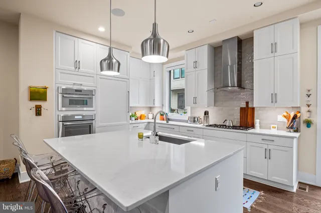 a kitchen that has a lot of white cabinets and stainless steel appliances