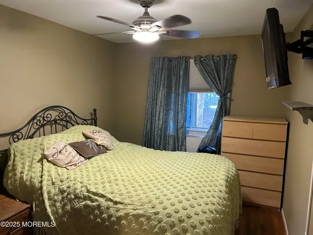 a bedroom with a bed and dresser with wooden floor