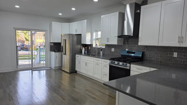 a large kitchen with stainless steel appliances granite countertop a stove a sink and a refrigerator