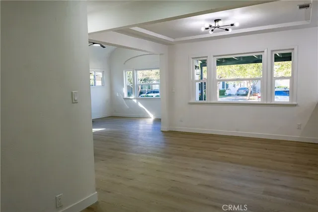 a view of an empty room with a window and wooden floor