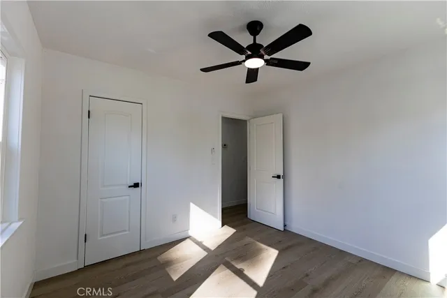 an empty room with wooden floor fireplace and windows