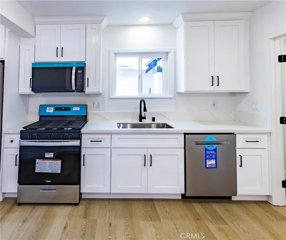 a kitchen with stainless steel appliances a stove a microwave a sink and cabinets