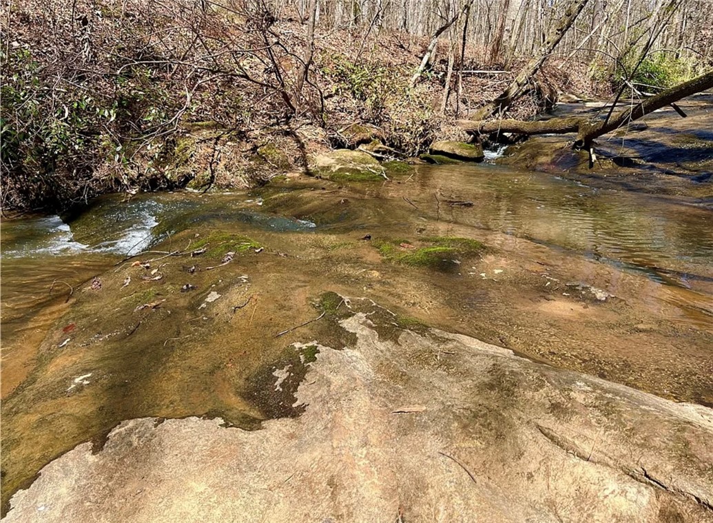 0 Smith McGee Road Iva, SC 29655 - Photo 3 of 10 A tranquil creek flows over natural rock formations, creating a serene outdoor escape.