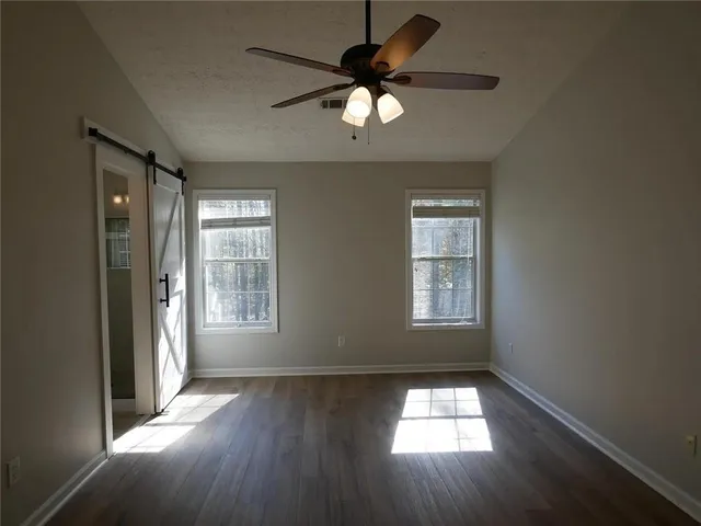an empty room with wooden floor and windows