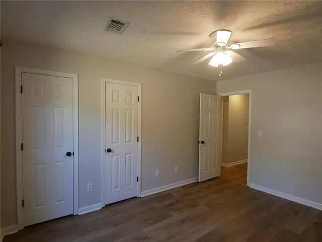 an empty room with wooden floor closet and windows