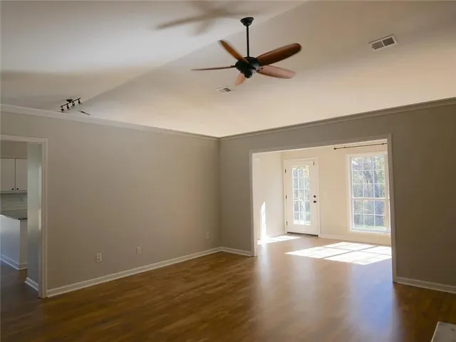 a view of an empty room with wooden floor and a window