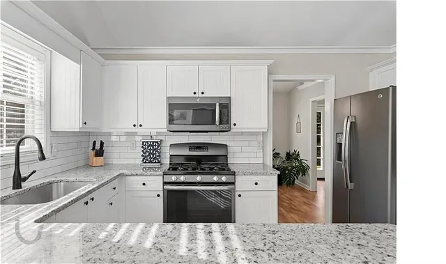 a kitchen with stainless steel appliances kitchen island granite countertop a sink stove and refrigerator