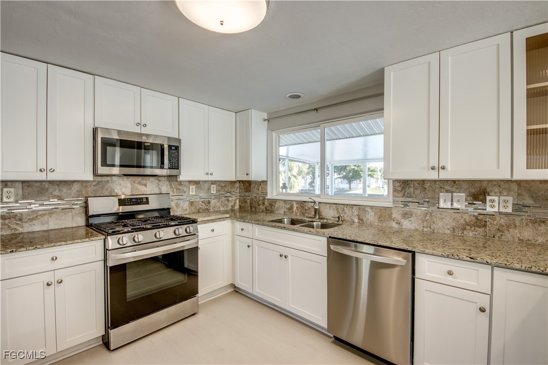12262 Boat Shell Drive Matlacha Isles, FL 33991 - Photo 19 of 39 a kitchen with granite countertop white cabinets white stainless steel appliances a sink and a window