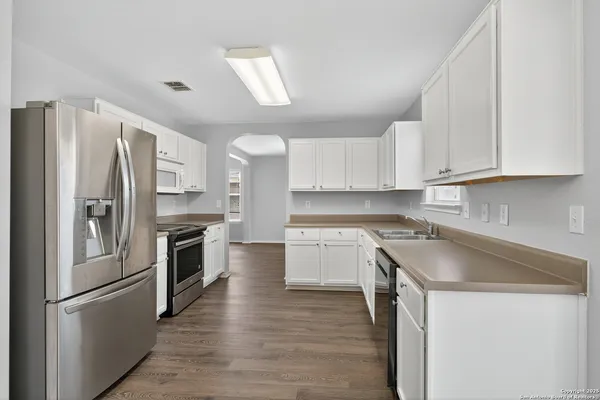 a kitchen with granite countertop a refrigerator stove and sink