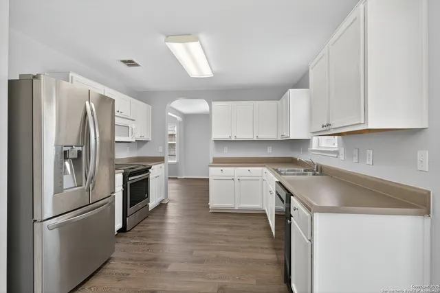 a kitchen with granite countertop a refrigerator stove and sink