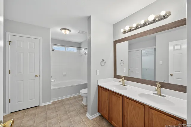 a bathroom with a double vanity sink a toilet a mirror and shower