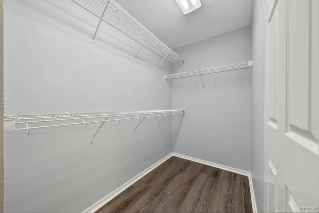 a view of an empty room with wooden floor and a ceiling fan