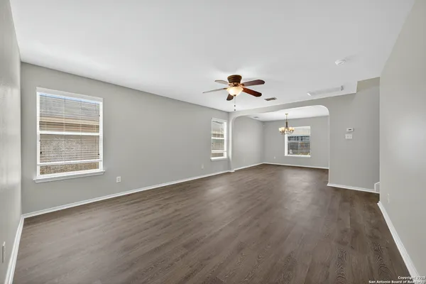 a view of an empty room with a window and wooden floor