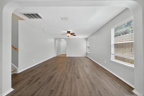 a view of empty room with wooden floor and fan