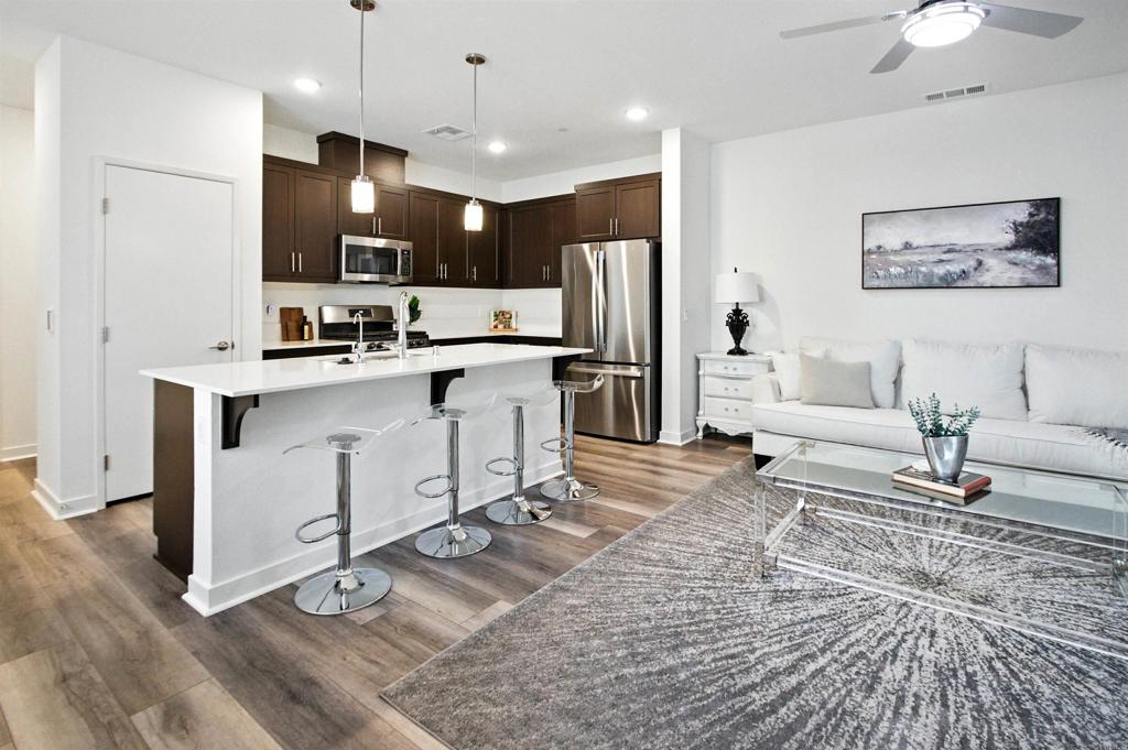 a living room with stainless steel appliances kitchen island granite countertop furniture a rug a fireplace and a kitchen view