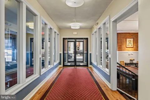 a view of a hallway with wooden floor and a bathroom