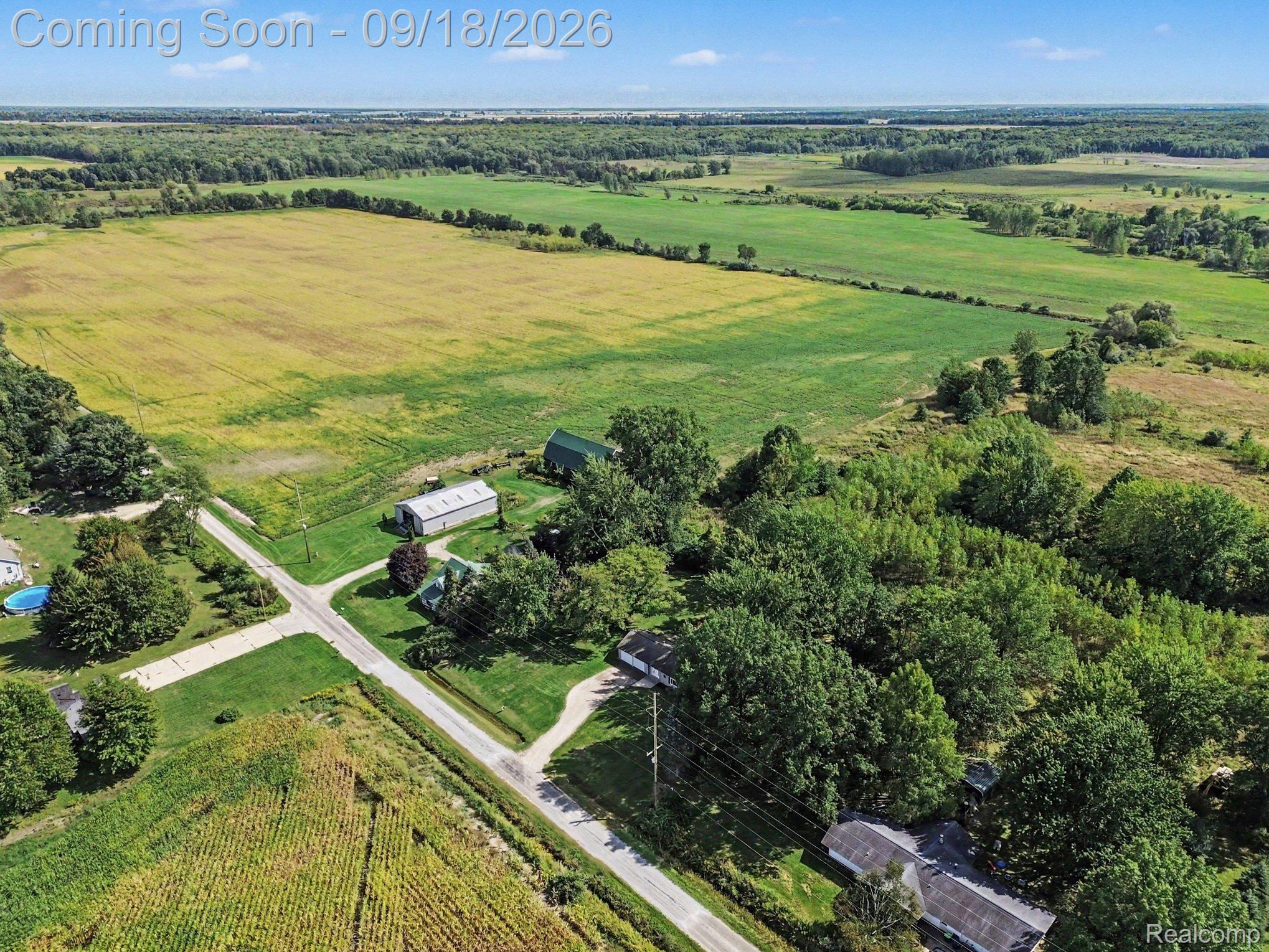 Expansive land parcel with surrounding agricultural fields, mature tree lines, and a rural road network