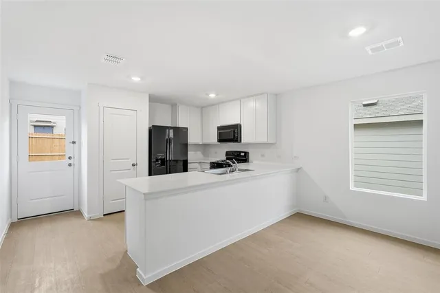 a kitchen with stainless steel appliances kitchen island sink refrigerator and cabinets