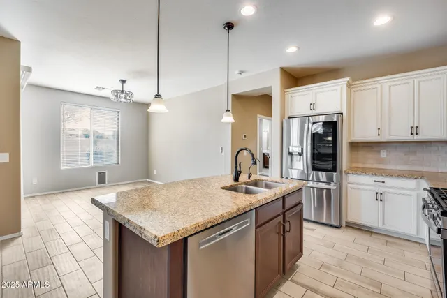 a kitchen with stainless steel appliances granite countertop a sink a stove and a refrigerator