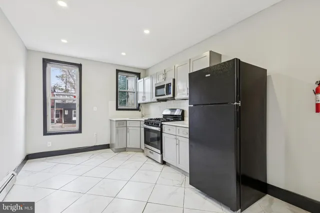 a kitchen with a refrigerator a stove top oven and cabinets