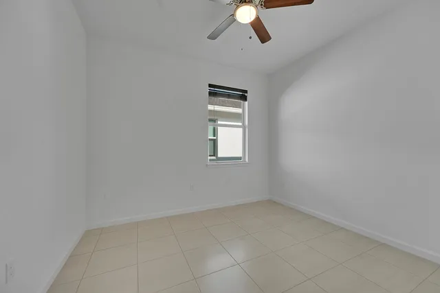 an empty room with a chandelier fan and windows