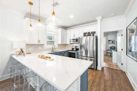 a kitchen with stainless steel appliances granite countertop a sink a stove a refrigerator and island with wooden floor