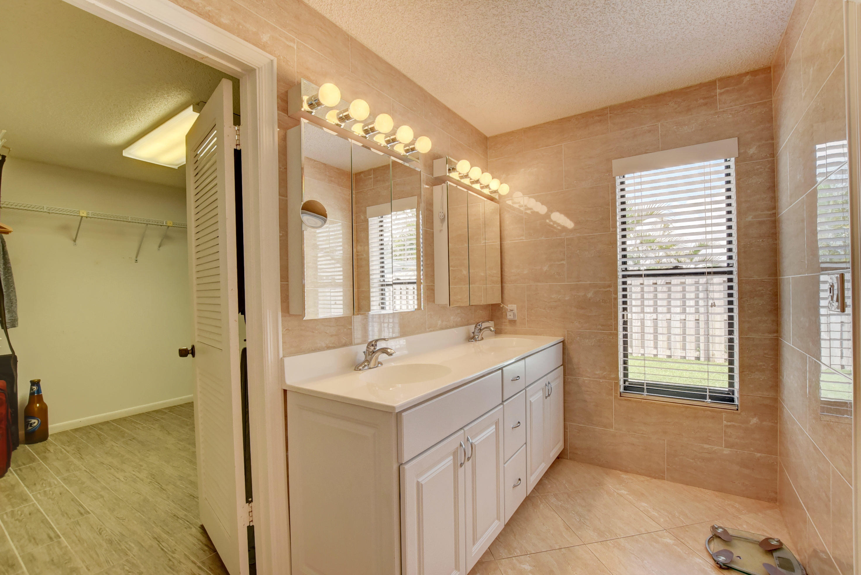 491 Northwest 72nd Street Boca Raton, FL 33487 - Photo 29 of 57 a spacious bathroom with a double vanity sink a large mirror and a bathtub