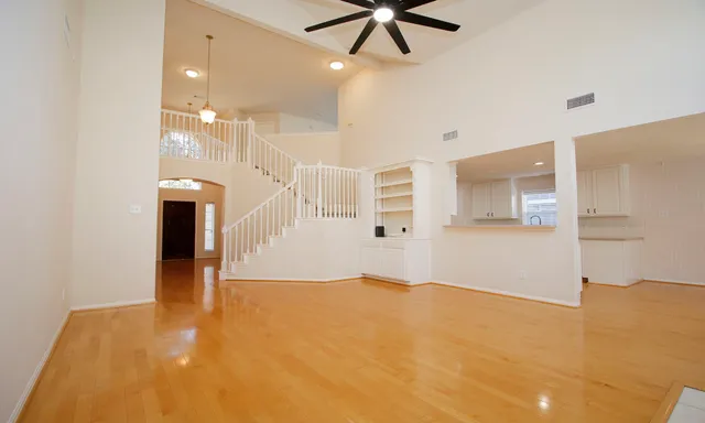 a view of a big room with entryway and chandelier fan
