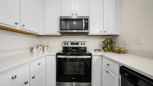 a kitchen with stainless steel appliances granite countertop white cabinets and a stove a oven with white countertops