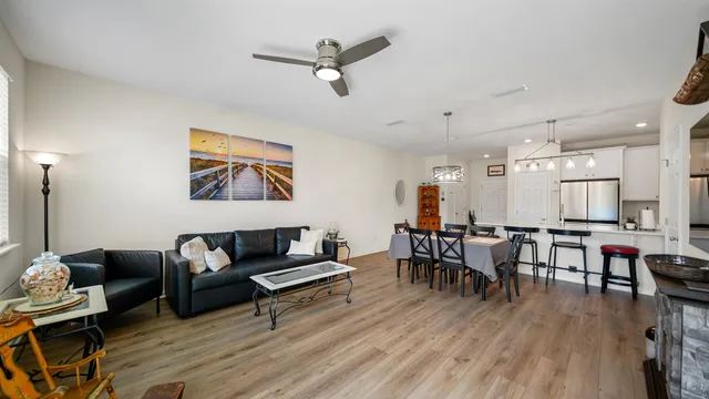 a living room with furniture kitchen view and a wooden floor